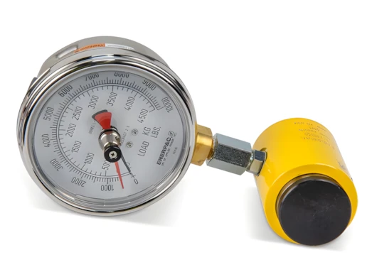 Industrial pressure gauge with chrome case and red needle, connected to a yellow air regulator.