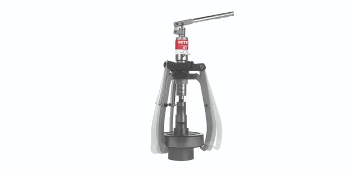 Compact hydraulic press head mounted on a tripod stand, featuring a red label on the central column for safety or identification