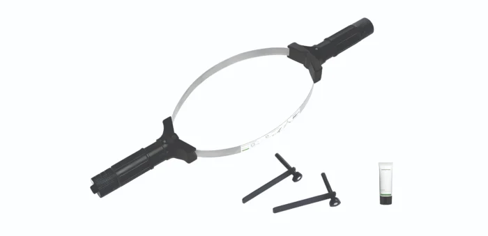 Medical device: circular frame with two black handles and a slender tube, likely a laparoscopic instrument used in minimally invasive surgery.