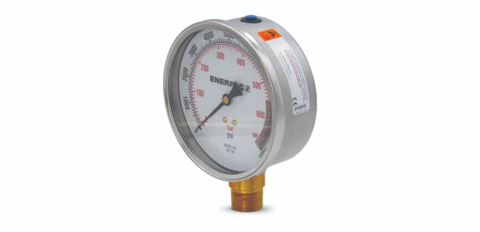 Round industrial pressure gauge with a metal case mounted on a brass connector, showing psi and bar scales on the dial (up to ~600 psi).